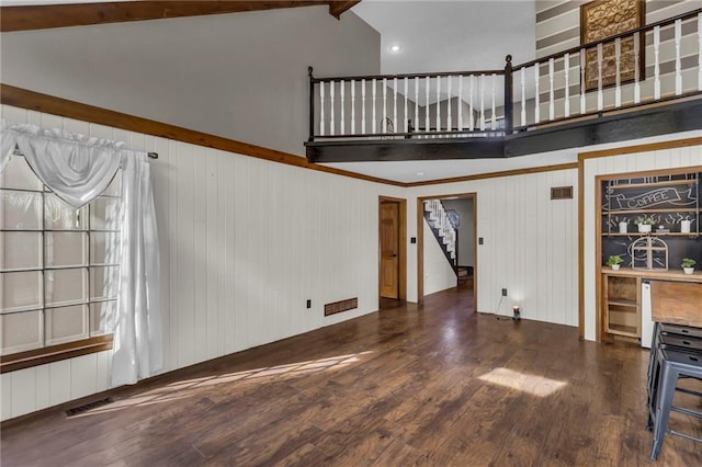 unfurnished living room with stairs, high vaulted ceiling, wood finished floors, and visible vents