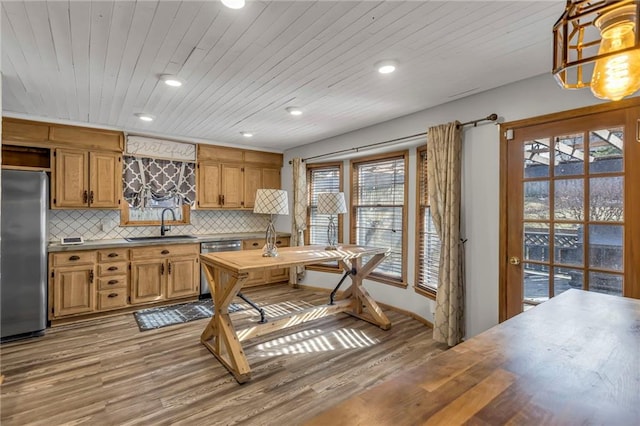 kitchen with stainless steel appliances, tasteful backsplash, wood ceiling, a sink, and wood finished floors