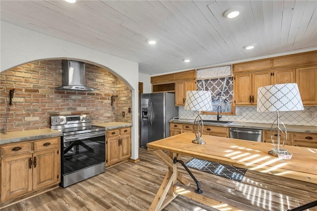 kitchen featuring stainless steel appliances, a sink, wood ceiling, wall chimney range hood, and backsplash