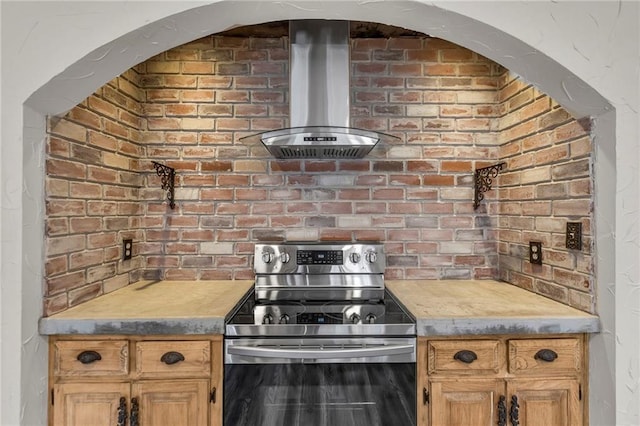 kitchen featuring arched walkways, light countertops, wall chimney range hood, and stainless steel electric stove