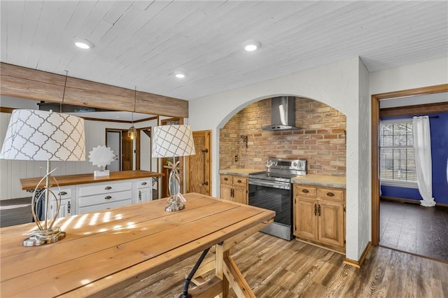 kitchen featuring stainless steel electric range, recessed lighting, butcher block counters, wood finished floors, and wall chimney exhaust hood