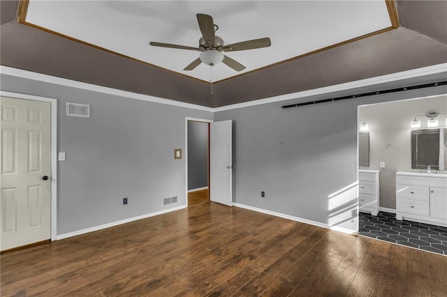 unfurnished bedroom featuring ensuite bathroom, hardwood / wood-style floors, a sink, and visible vents