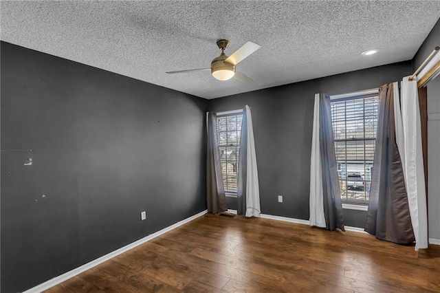 empty room featuring ceiling fan, a textured ceiling, baseboards, and wood finished floors