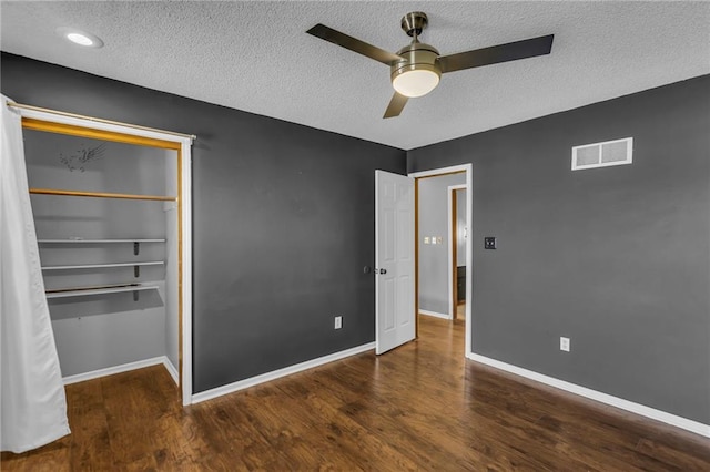 unfurnished bedroom with a textured ceiling, wood finished floors, visible vents, and baseboards