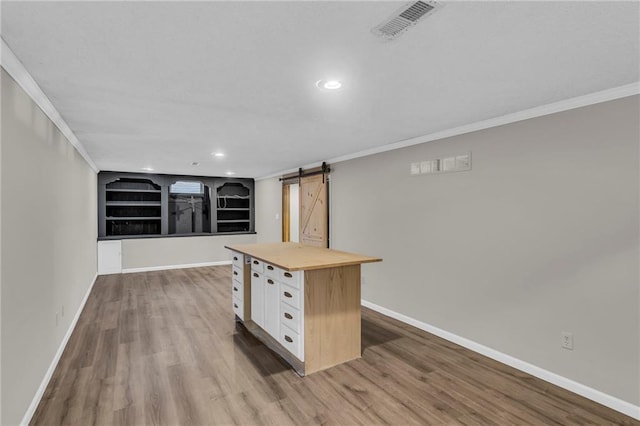 kitchen with ornamental molding, a barn door, butcher block counters, and visible vents