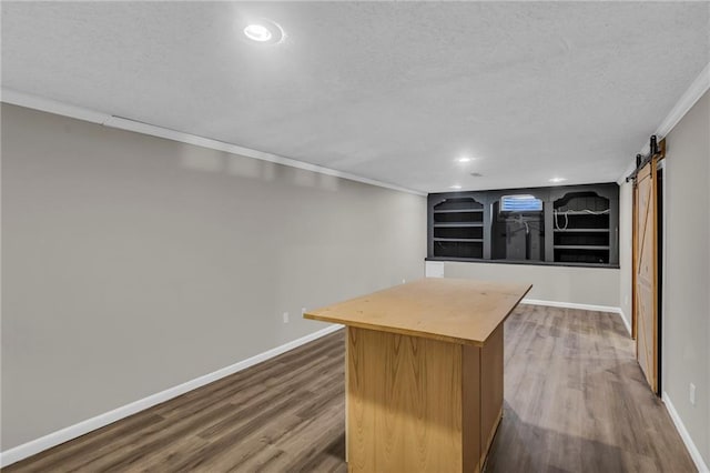 bar featuring a textured ceiling, a barn door, wood finished floors, baseboards, and crown molding