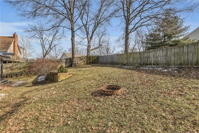 view of yard featuring a fenced backyard and a fire pit