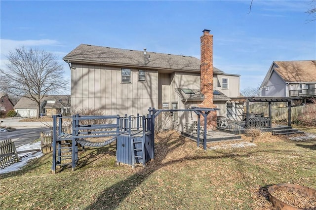 rear view of property with a chimney, fence, a pergola, and a lawn