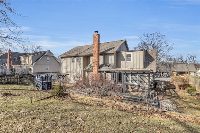 back of property with fence, a lawn, a residential view, board and batten siding, and a chimney