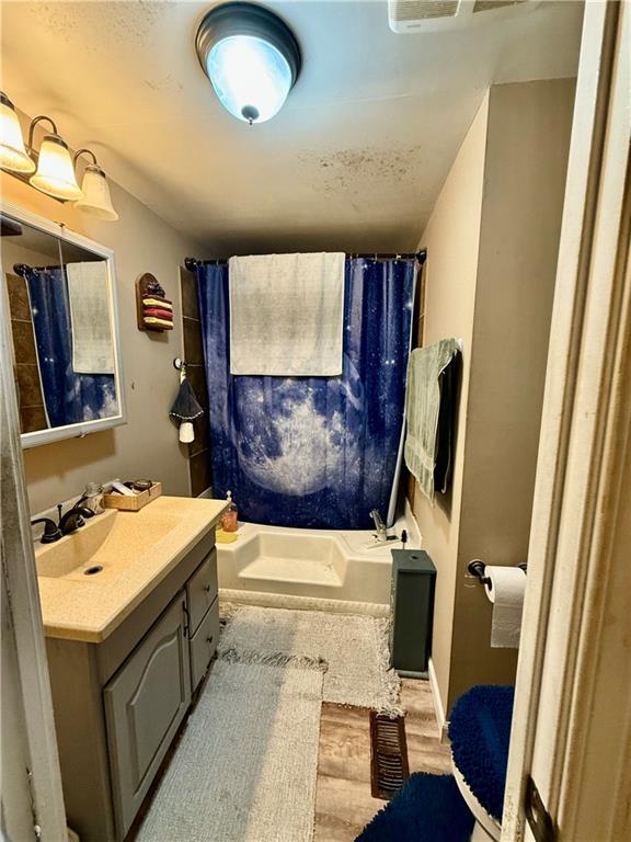 bathroom featuring hardwood / wood-style flooring, shower / tub combo with curtain, and vanity