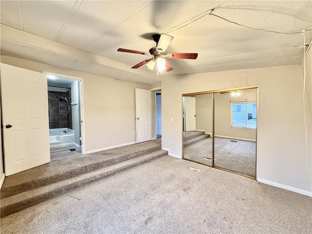 unfurnished bedroom with ensuite bathroom, a closet, ceiling fan, and carpet