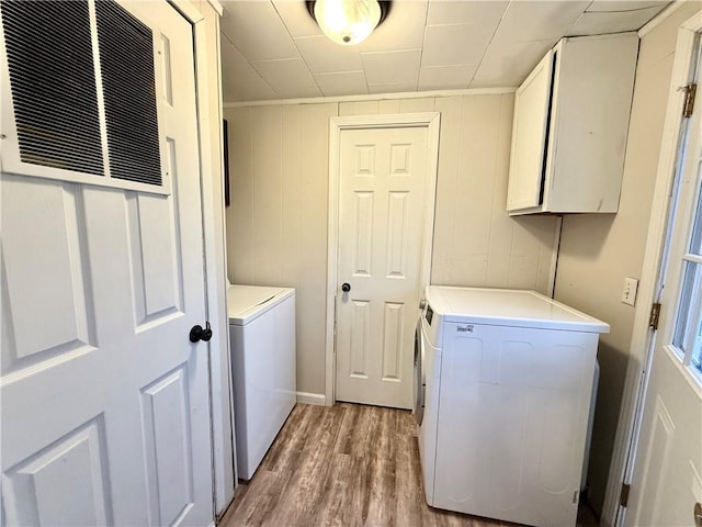 clothes washing area featuring cabinets, hardwood / wood-style floors, and washer and dryer