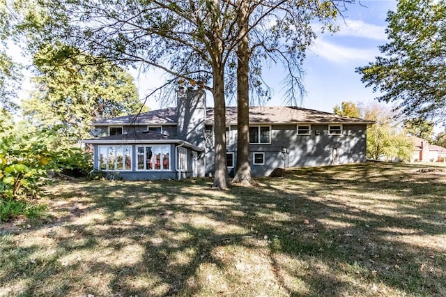 rear view of property featuring a sunroom and a yard