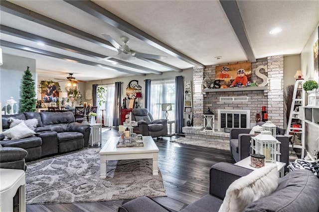 living room with hardwood / wood-style flooring, ceiling fan, beam ceiling, and a brick fireplace