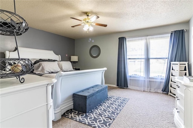 bedroom with ceiling fan, light colored carpet, and a textured ceiling