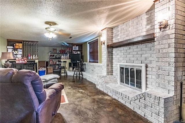 living room with ceiling fan, brick wall, concrete flooring, a textured ceiling, and a fireplace