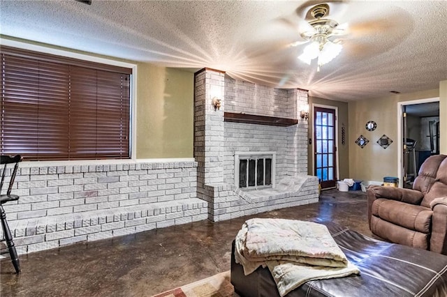 living room featuring ceiling fan, a fireplace, concrete flooring, and a textured ceiling