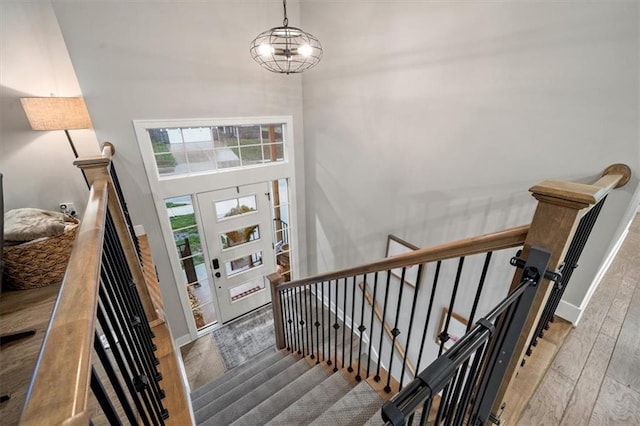 foyer with a chandelier, a towering ceiling, and wood-type flooring