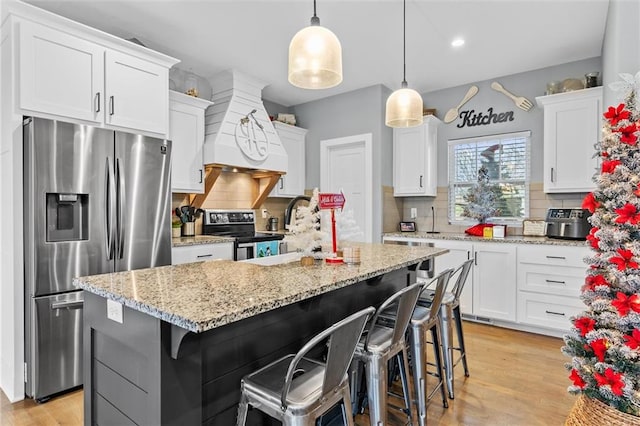 kitchen with white cabinets, a center island, appliances with stainless steel finishes, and tasteful backsplash