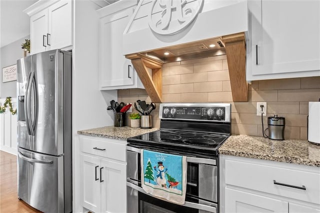 kitchen featuring white cabinets, light hardwood / wood-style flooring, light stone countertops, custom range hood, and stainless steel appliances