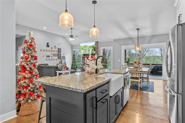 kitchen featuring ceiling fan, sink, stainless steel appliances, an island with sink, and light hardwood / wood-style floors