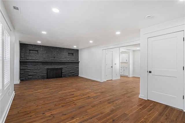 unfurnished living room featuring dark hardwood / wood-style floors and a stone fireplace