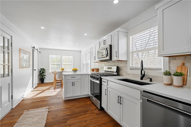 kitchen with white cabinetry, sink, dark wood-type flooring, backsplash, and appliances with stainless steel finishes