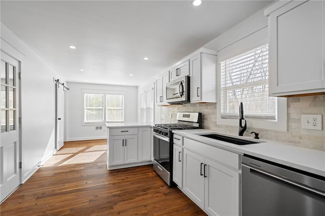 kitchen featuring dark wood-type flooring, sink, decorative backsplash, appliances with stainless steel finishes, and white cabinetry