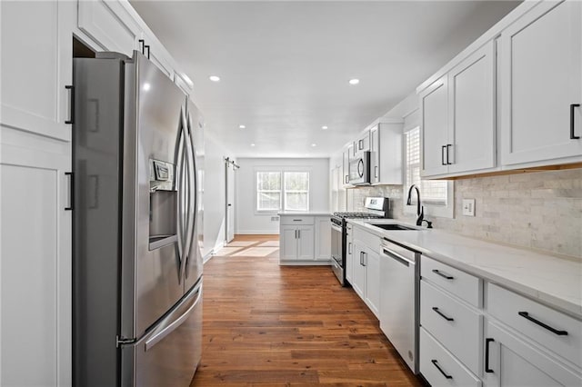 kitchen featuring backsplash, white cabinets, sink, appliances with stainless steel finishes, and dark hardwood / wood-style flooring