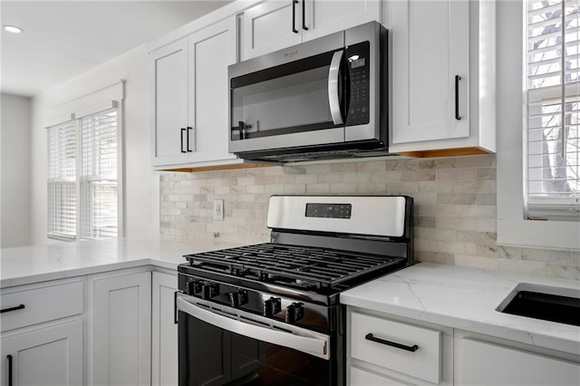 kitchen with white cabinetry, a healthy amount of sunlight, tasteful backsplash, and stainless steel appliances