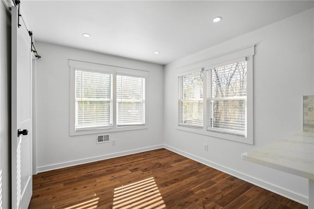 unfurnished room featuring a barn door and dark wood-type flooring