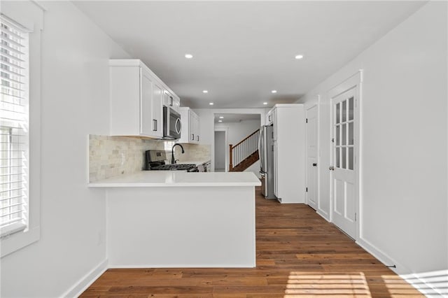 kitchen featuring kitchen peninsula, a wealth of natural light, dark hardwood / wood-style flooring, and stainless steel appliances