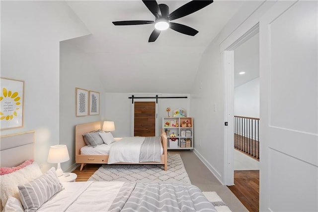 bedroom with a barn door, ceiling fan, light hardwood / wood-style floors, and lofted ceiling