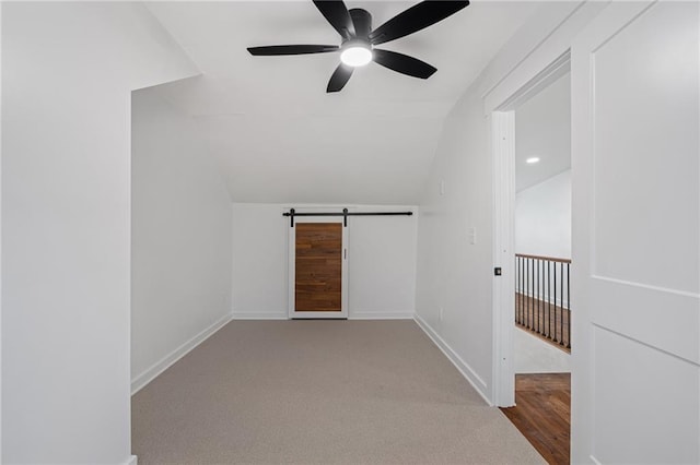 additional living space featuring ceiling fan, a barn door, light colored carpet, and lofted ceiling