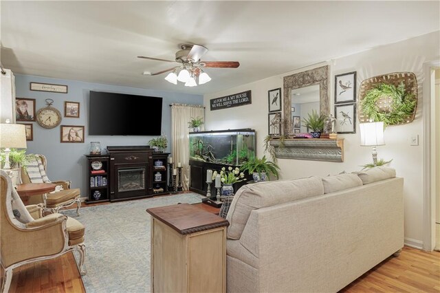 living room featuring a fireplace, light hardwood / wood-style floors, and ceiling fan