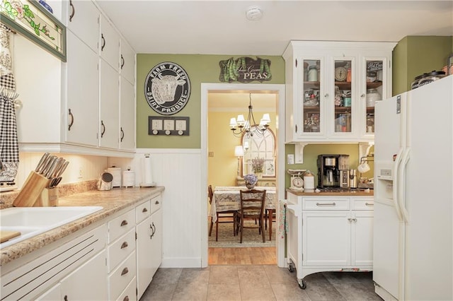 kitchen featuring white fridge with ice dispenser, white cabinets, a chandelier, decorative light fixtures, and light tile patterned flooring