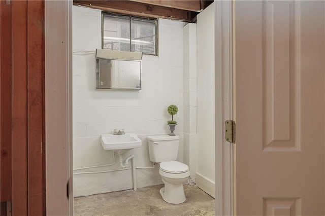 bathroom featuring toilet, concrete flooring, and sink