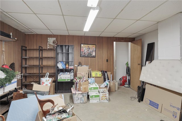 basement with a paneled ceiling and wood walls