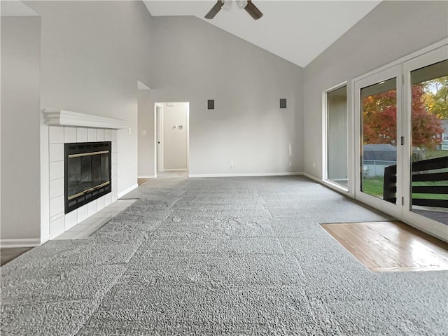 unfurnished living room with a tile fireplace, ceiling fan, carpet floors, and high vaulted ceiling