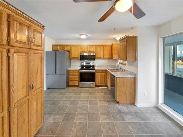 kitchen featuring stainless steel appliances, dark tile patterned flooring, ceiling fan, and sink