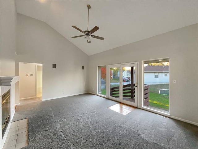 unfurnished living room with a tiled fireplace, ceiling fan, high vaulted ceiling, and light colored carpet