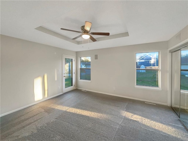 carpeted empty room featuring a tray ceiling and ceiling fan