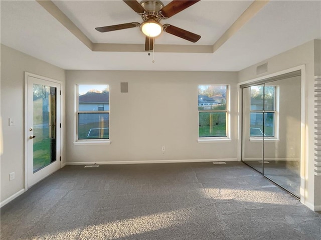 carpeted spare room with a tray ceiling and ceiling fan