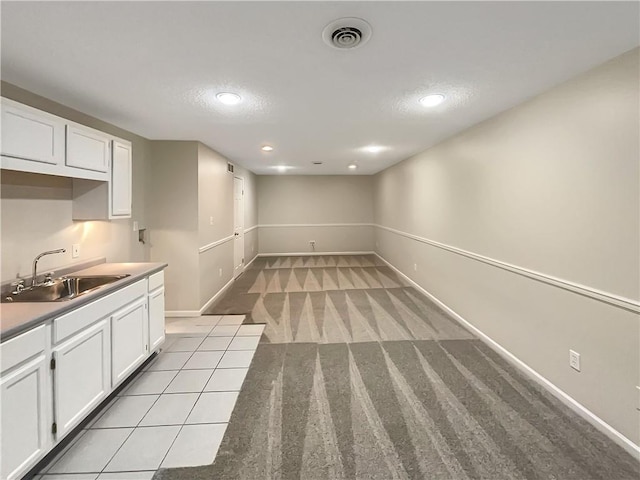 kitchen with white cabinets, light carpet, a textured ceiling, and sink