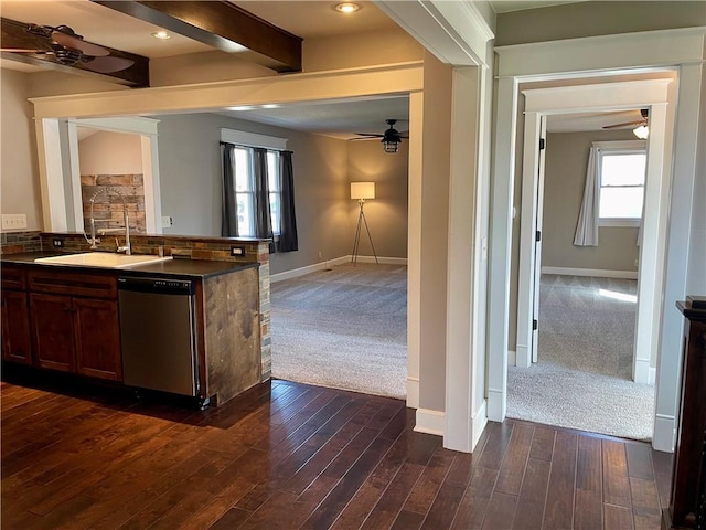 kitchen featuring a sink, stainless steel dishwasher, dark countertops, dark colored carpet, and ceiling fan