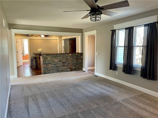 unfurnished living room featuring ceiling fan, a textured ceiling, and carpet