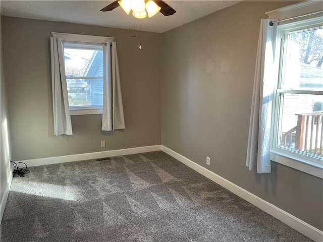 spare room with baseboards, dark carpet, and a ceiling fan