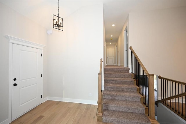 stairs featuring an inviting chandelier and wood-type flooring