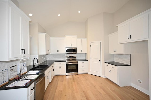 kitchen with sink, white cabinets, backsplash, stainless steel appliances, and light hardwood / wood-style flooring