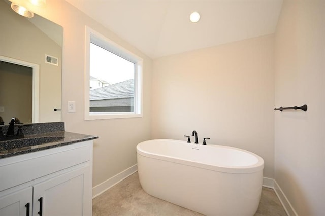 bathroom with vanity, vaulted ceiling, and a bathing tub